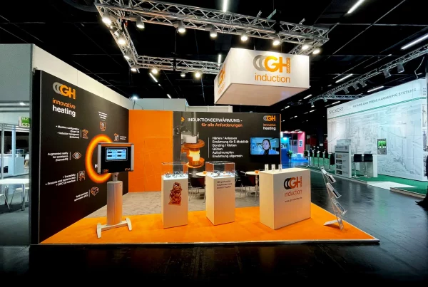 Messestand von GH Group mit Monitoren und Pulten.